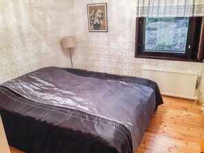 A bedroom with a bed, a lamp, a window, and a radiator. - Pippuriranta by Interhome (Sipoo)