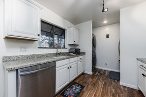 Kitchen features a window, stainless steel dishwasher, and a toaster on the granite countertop.