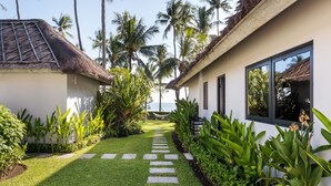 A resort with a thatched-roof building, a well-maintained garden with a stone pathway, and a view of the ocean. - Renovated 3BR Villa W/ Pool - Perfect for Couples , Bali Villa 2237 (Bali)