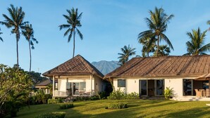 A resort with two buildings, each with a thatched roof, surrounded by palm trees and a mountain in the background. - Renovated 3BR Villa W/ Pool - Perfect for Couples , Bali Villa 2237 (Bali)