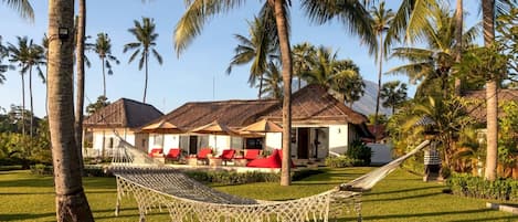 A resort with multiple rooms, a hammock, and palm trees.