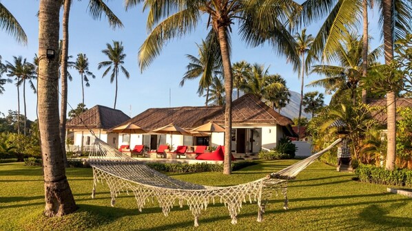 A resort with multiple rooms, a hammock, and palm trees.