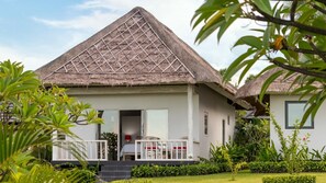 A bungalow with a thatched roof, a covered porch, and a well-maintained garden.