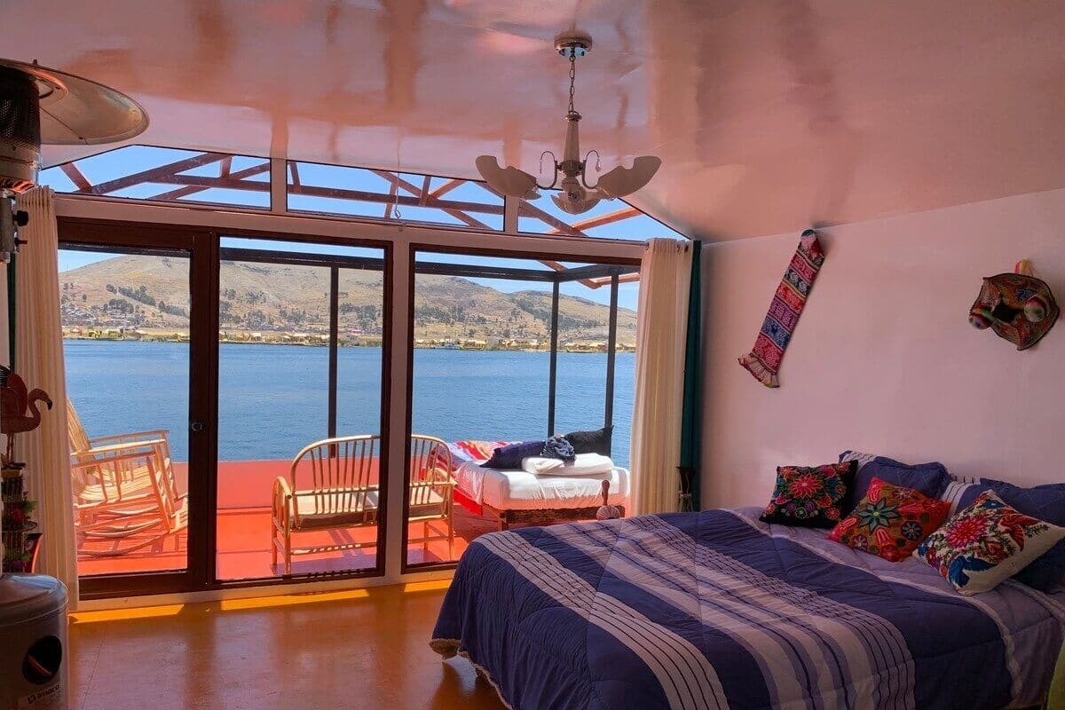 A bedroom with a large bed, a view of the lake, and a balcony with chairs.
