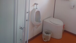 Et badeværelse med pissoir, toilet og skraldespand.
