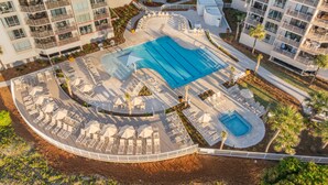 An aerial view of a resort with a large central pool, sun loungers, and a landscaped deck area. - Oceanfront at Villamare! Pool and Ocean Views. (Hilton Head Island)
