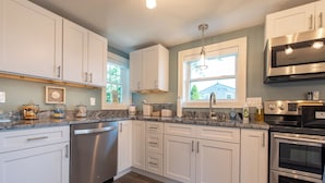A modern kitchen with white cabinets, stainless steel appliances, and a granite countertop.