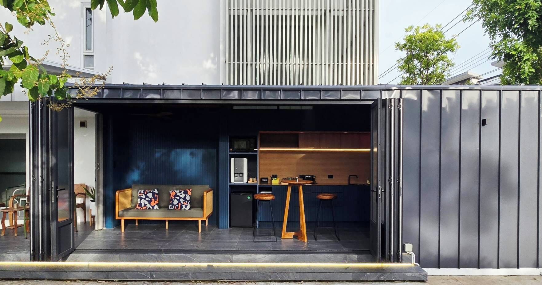 Un espacio habitable moderno y compacto, con sofá, pequeña cocina y mesa de comedor.
