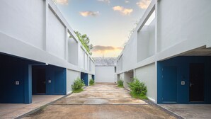 A modern building with a central courtyard, featuring a pathway leading to a covered area with a tiled roof.