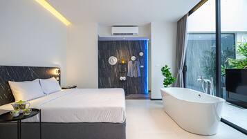 A modern bedroom with a large bed, a built-in bathtub, and a shower area.
