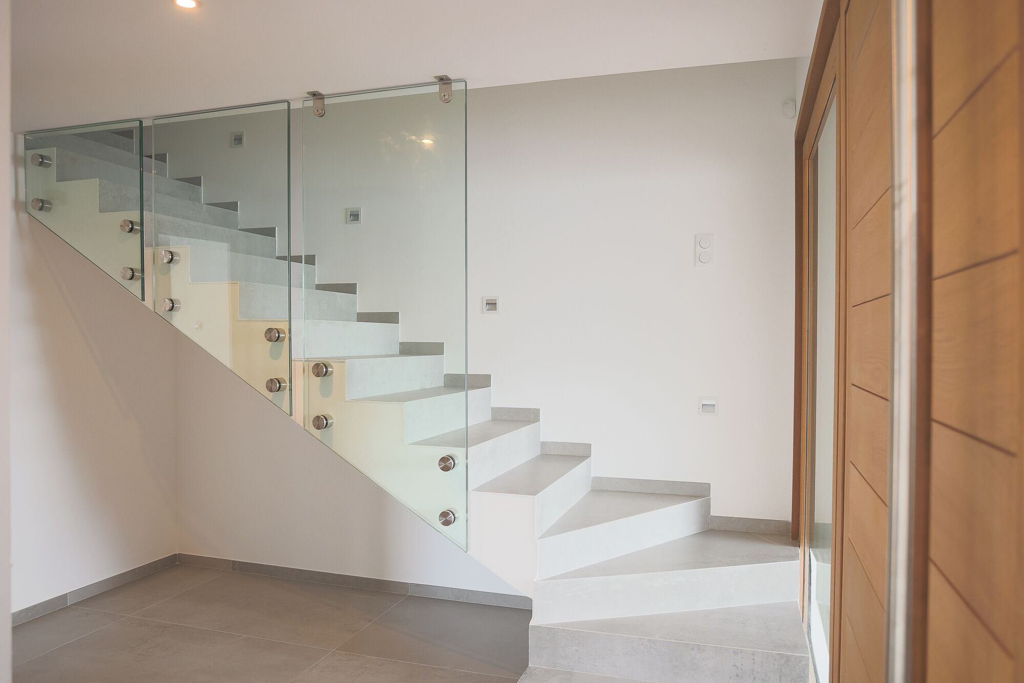 A modern staircase with glass railings and a wooden door.