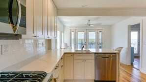 Una cocina moderna con armarios blancos, un lavavajillas de acero inoxidable y una estufa empotrada.