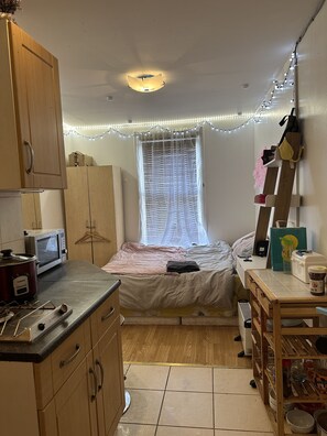 Cozy retreat with a single bed, kitchenette, and wooden cabinet.