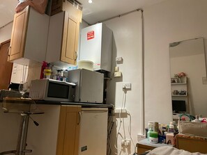 Kitchen area with refrigerator, microwave, and countertop space for preparation and storage.