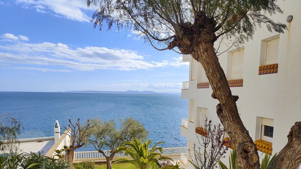 A coastal hotel with a view of the sea, a staircase leading to the entrance, and a well-maintained garden. - VACATION ON THE ROCKS, 1ST LINE OF SEA, PRIVILEGED AREA, SEA VIEW. (Roses)