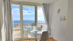 A balcony with a table and chairs, a view of the sea, and a white wall with a light fixture. - VACATION ON THE ROCKS, 1ST LINE OF SEA, PRIVILEGED AREA, SEA VIEW. (Roses)