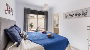 Ein Schlafzimmer mit einem Bett, Kissen, einer Decke, einer Pendelleuchte und einer Wand mit Hundeabbildungen.