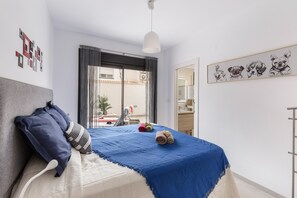 Un dormitorio con cama, almohadas, una colcha, una lámpara colgante e ilustraciones de perros en la pared.