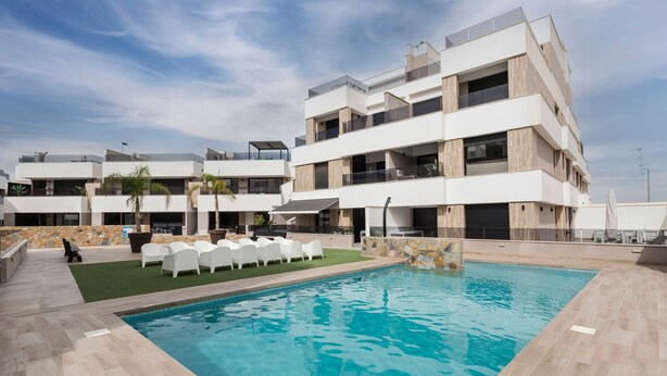Ein modernes Hotel mit Schwimmbad, Außenbereich und einer Steinwand.