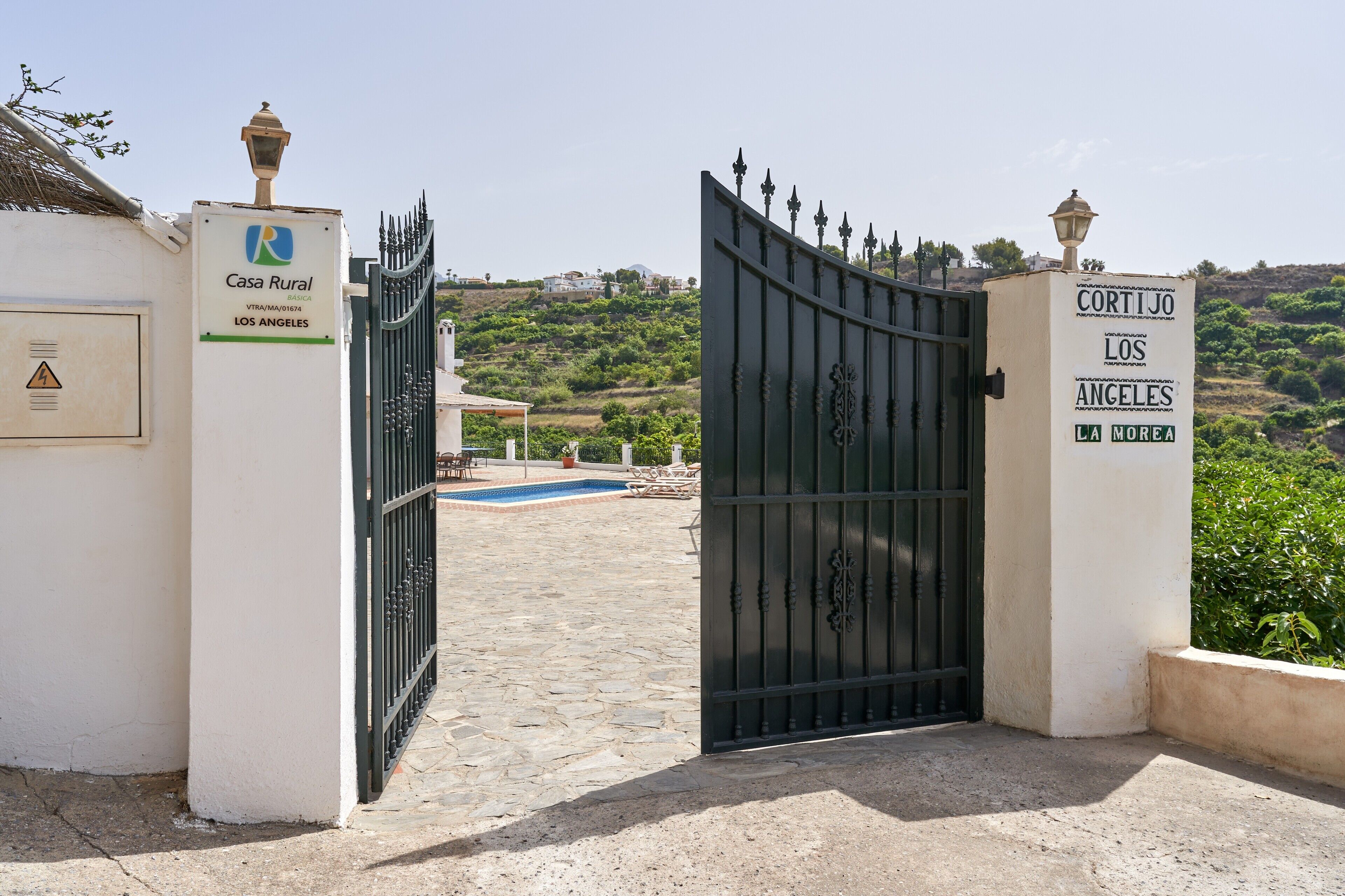 A gated entrance to a property named 'Casa Rural Los Angeles' with a pool and a view of a hillside.