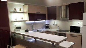Une cuisine moderne dotée d’un îlot central, d’appareils électroménagers intégrés et d’un design minimaliste.