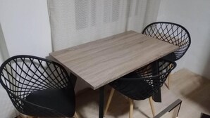 Un coin repas avec une table en bois et deux chaises à armature métallique noire.