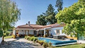 Une maison avec une piscine, un patio couvert et un jardin.