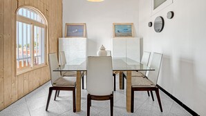 A dining area with a glass table, wicker chairs, and a wooden wall.