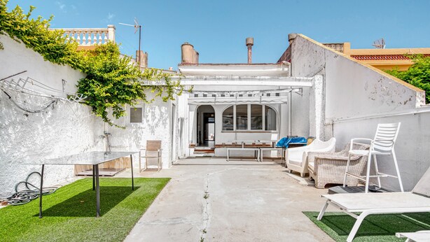 A courtyard with a white table, chairs, and a bench.
