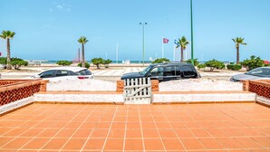 A parking area with cars, a gate, and palm trees.