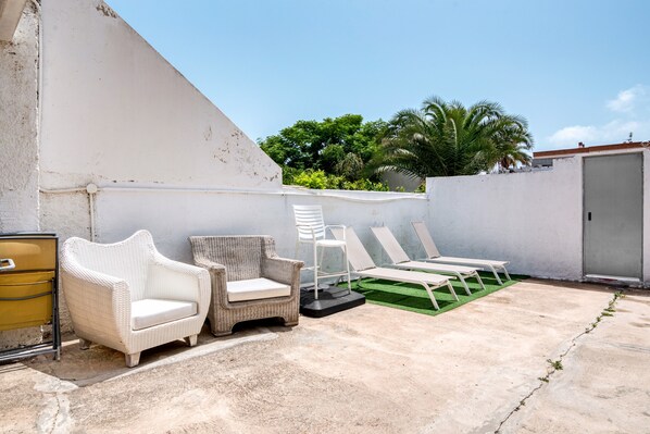 Una terraza en la azotea con sillones de descanso, un sofá de mimbre y una mesita.