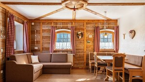 A cozy room with wooden walls, a sofa, a dining table with chairs, and a bench.