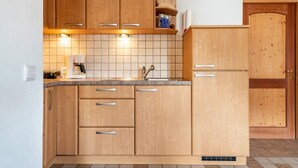 A kitchen with wooden cabinets, a countertop, a sink, and a door.