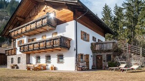 A two-story chalet with a balcony, stone foundation, and wooden exterior.