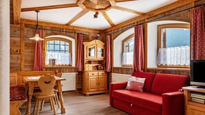 Un intérieur en bois comprenant une table à manger, des chaises, un canapé rouge, un meuble en bois et un téléviseur.