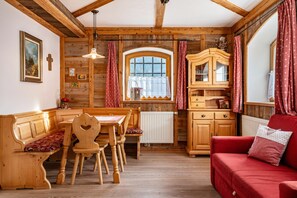 Un intérieur en bois comprenant une table à manger, des chaises, un canapé rouge et un meuble.