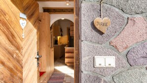Une porte en bois ornée d’une plaque en forme de cœur sur laquelle est inscrit le mot « BIRKE », et un mur en pierre avec deux interrupteurs.