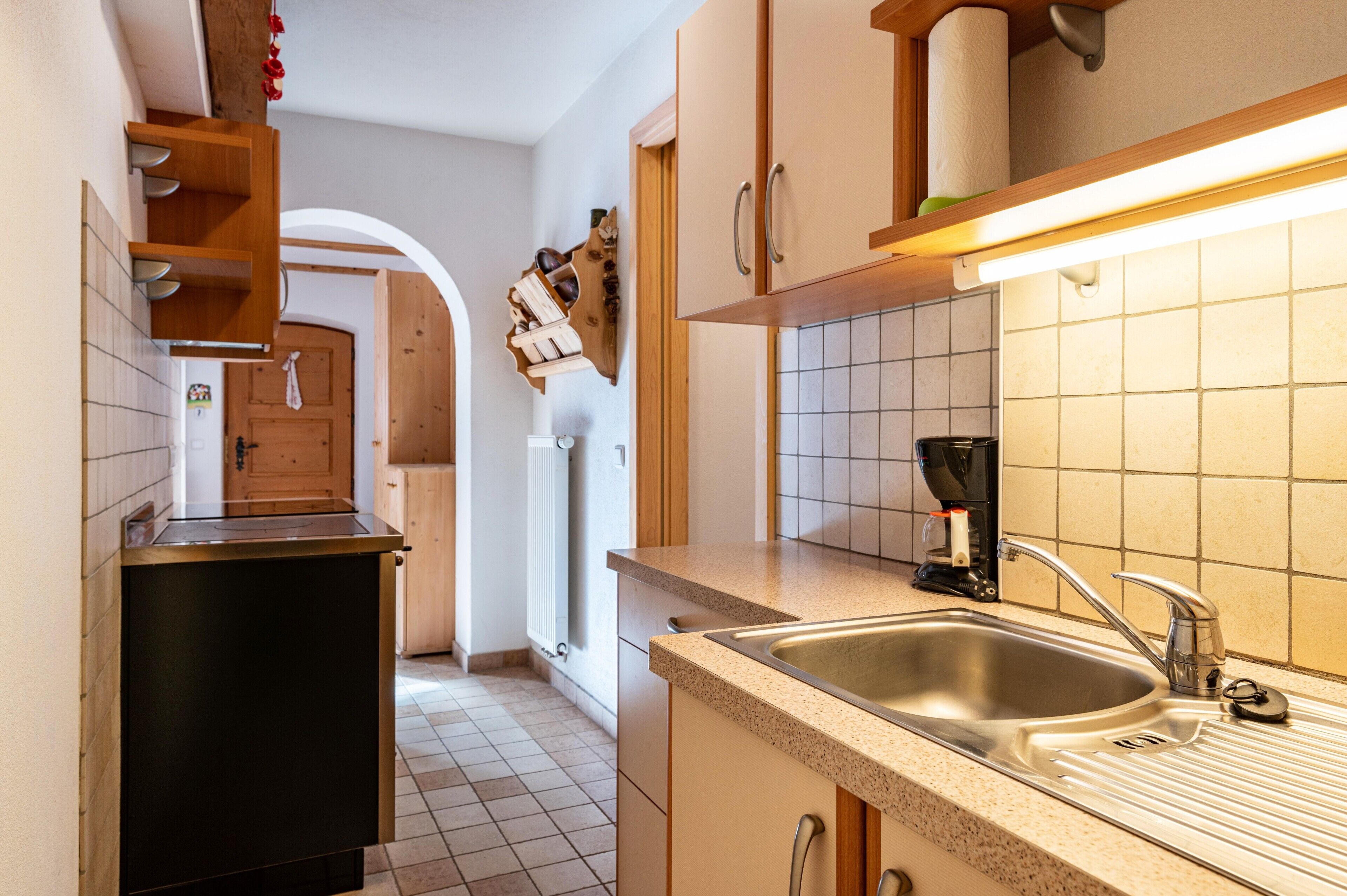 A kitchen with a sink, countertop, and wooden cabinets.