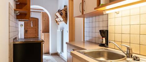 A kitchen with a sink, countertop, and wooden cabinets.