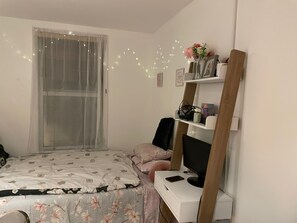 Cozy retreat with a neatly made bed, desk, and shelf unit, perfect for relaxation and productivity.