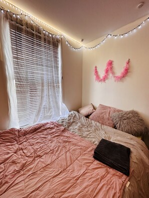 Cozy retreat with a neatly made bed, featuring a pink quilted bedspread and plush pillows.