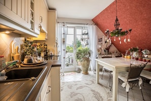 A kitchen with a sink, a dining table with chairs, a chandelier, and a large potted plant. - Apartment 'Die Kleine Oase 3  Im Wohnhaus' (Stuhr)
