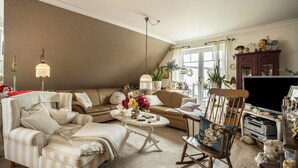 A living room with a sofa, armchair, coffee table, and a television.