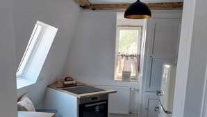 Une cuisine de taille réduite, dotée d’un four encastré, d’une fenêtre et d’un ventilateur de plafond.