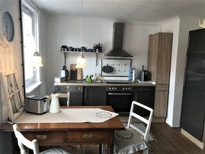 Une cuisine compacte équipée d’une cuisinière, d’un évier et d’un coin repas avec une table et des chaises.