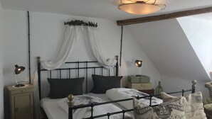 Ein Schlafzimmer mit Bett, Nachttischlampen, einem Nachttisch, einer Bank und einer Deckenleuchte.