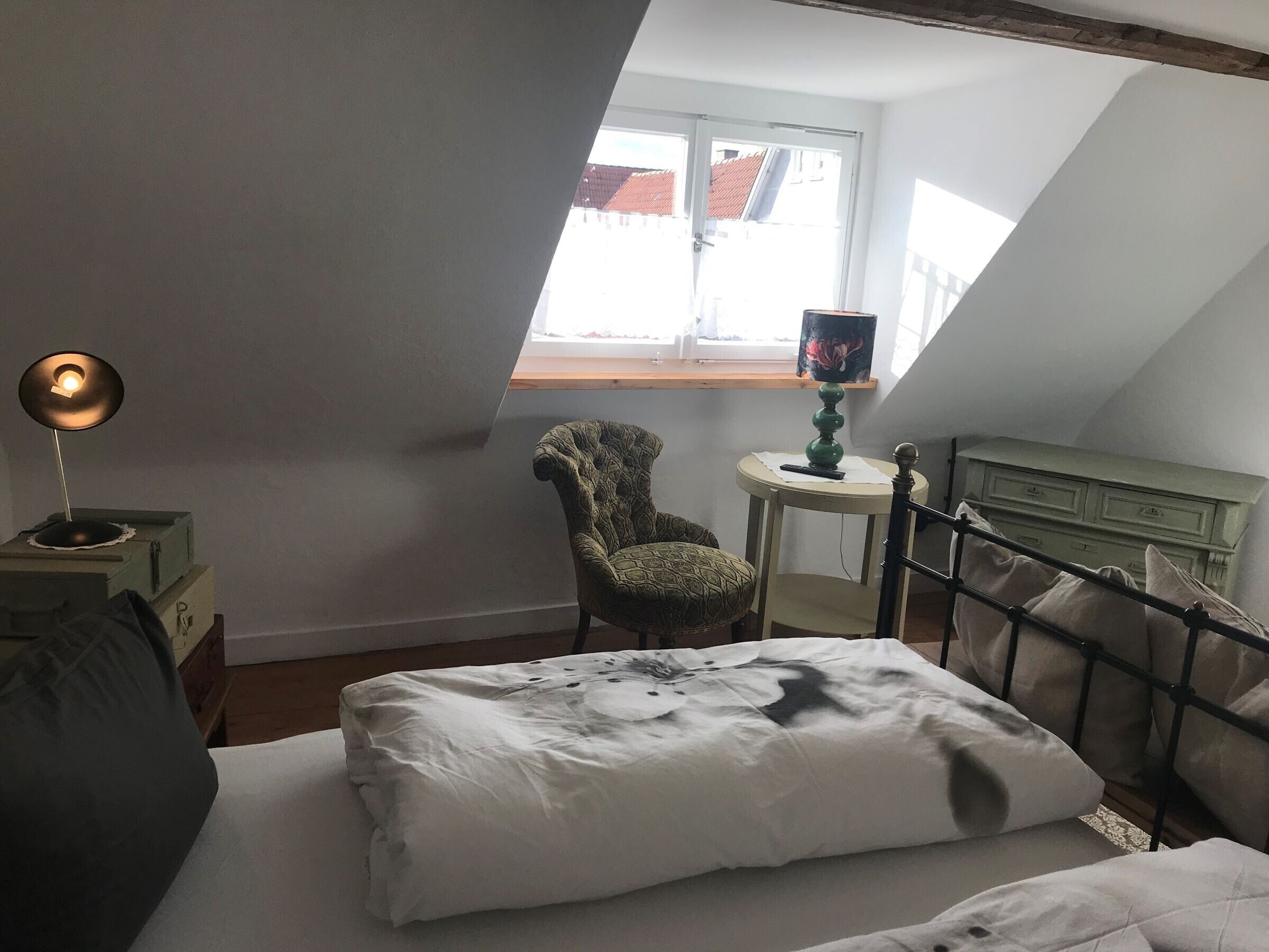 Une chambre à coucher avec un lit, une chaise, une petite table et une lampe.