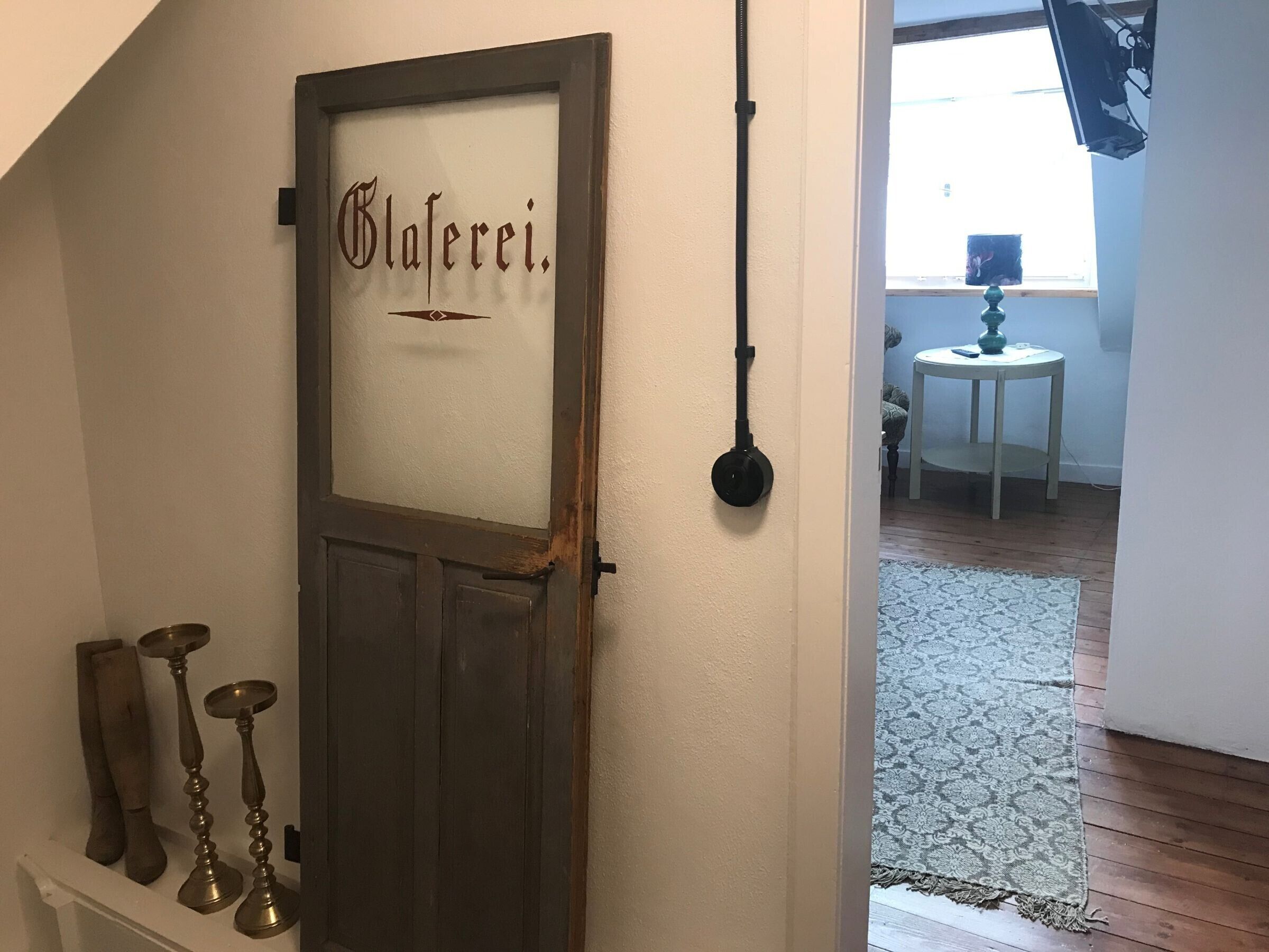 A door with the name 'Glaferei' and a black hanging object on the wall.