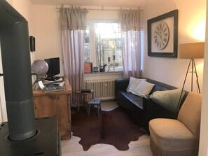 Un salon chaleureux avec un canapé noir, une petite table en bois, un globe terrestre et un radiateur.