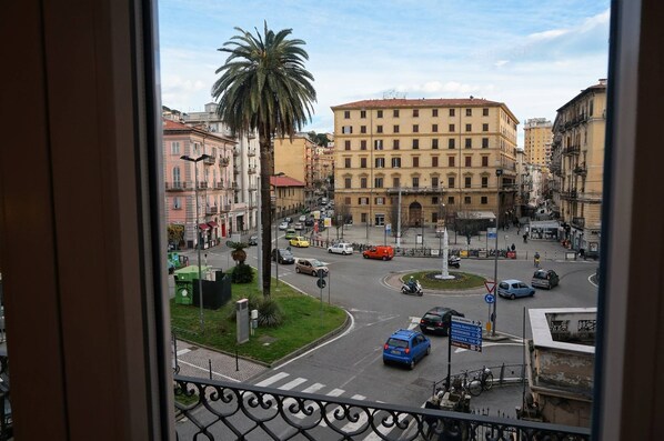 A city street with buildings, a palm tree, and a roundabout.
